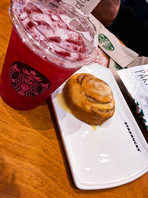 Starbucks咖啡店的白色碟子上的紅色冰凍飲品和肉桂卷。 — 星巴克 壁紙