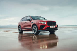 紅色 Bentley SUV 停泊喺濕沙灘上，有倒影 — MacBook Air M3 壁紙