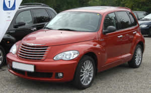 紅色Chrysler PT Cruiser泊喺碎石停車場，後面有樹木。 — Steam Deck 壁紙