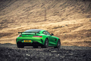 綠色Mercedes-AMG GT R跑車在碎石路上，背景有草坡。 — 綠色動態圖 壁紙
