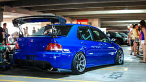 藍色改裝跑車，帶有大型後擾流板，停在地下車庫，附近有人。 — Jdm 美學 壁紙