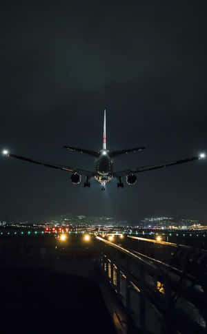 夜間降落的飛機，下方城市燈光閃爍。 — 天空景觀 壁紙
