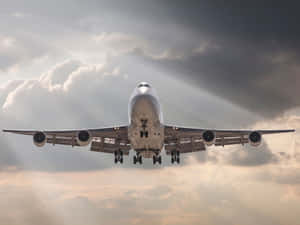 從下方觀看一架大型客機穿過雲層下降，陽光穿透雲層。 — 飛機 壁紙
