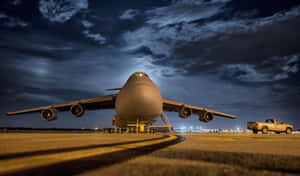 夜間機場停機坪上的大型貨機，旁邊有一輛皮卡車。 — 天空景觀 壁紙