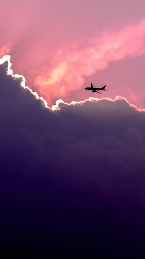飛機飛過粉紅和紫色的日落雲層 — 天空景觀 壁紙