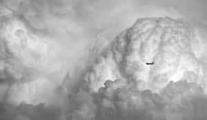 一架小飛機在灰階天空的濃密雲層中飛行。 — 唯美雲朵動態 壁紙