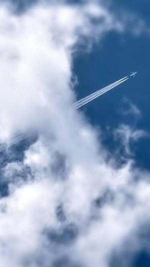 一架飛機在雲層上方高空飛行，在藍天上留下白色凝結尾跡。 — 藍天 壁紙