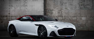 白色Aston Martin跑車帶紅色飾邊，停泊在佈滿塗鴉的混凝土牆前。 — 2560x1080 壁紙