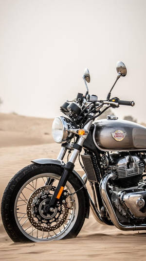 復古 Royal Enfield 電單車停泊在沙質沙漠地形上。 — 皇室 壁紙