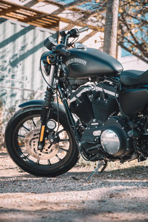 黑色Harley-Davidson電單車停在木結構下的碎石地上。 — 機車 壁紙