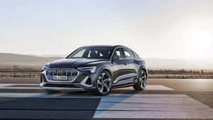 Audi e-tron S電動車在日落時分停在鋪砌道路上，背景有山丘。 — Audi R8 GIF 壁紙