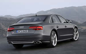 灰色Audi S8房車停泊在道路上，背景有山脈。 — Steam Deck OLED 壁紙