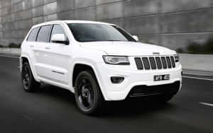 白色Jeep Grand Cherokee在模糊動態背景的城市道路上行駛。 — 16:10 壁紙