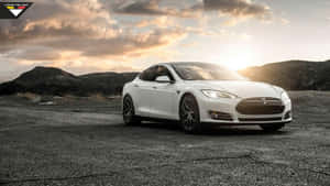 白色Tesla Model S在日落時停泊在裂開的瀝青路上，背後有山丘。 — Tesla GIF 壁紙