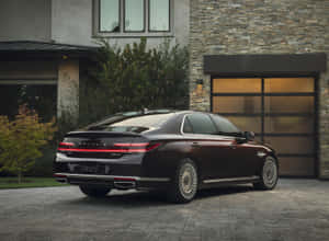 黃昏時分，酒紅色Genesis G90豪華轎車停泊在現代石屋前。 — 暮光 壁紙