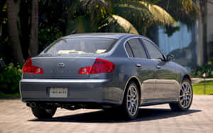 銀色 Infiniti G35 房車停泊在磚砌車道上，旁邊有棕櫚樹。 — Steam Deck OLED 壁紙