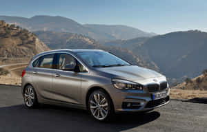 銀色BMW 2系Active Tourer停泊在山路上，背景有山丘。 — MacBook Air M2 壁紙