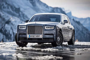 豪華勞斯萊斯 Ghost 在結冰的道路上，背景是白雪覆蓋的山脈。 — MacBook Pro M2 壁紙