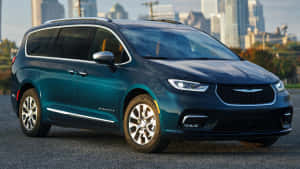 青綠色 Chrysler Pacifica 小型貨車停泊在日落時分的城市天際線前。