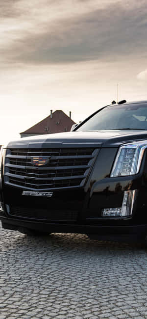 日落時分鵝卵石街道上的黑色 Cadillac Escalade — OnePlus Open 壁紙