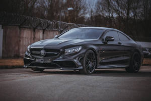 黑色Brabus Mercedes-AMG S 65 Coupe停泊在帶刺鐵絲網圍欄附近。 — 汽車 壁紙