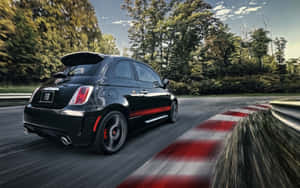 黑色Fiat 500 Abarth在森林道路上飛馳，帶有紅白護欄。 — Steam Deck 壁紙
