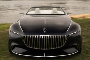 黑色Maybach開篷車，白色內飾，停在近水的草地上。 — Surface Pro 壁紙