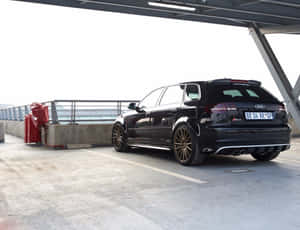 黑色奧迪RS3 Sportback配金色輪圈停泊在鋼橋下。 — 奧迪 GIF 壁紙