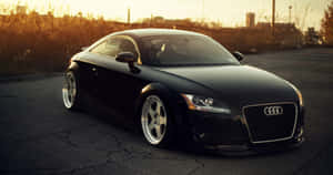 金色時刻，黑色奧迪TT跑車停泊在龜裂的瀝青路上。 — Audi R8 GIF 壁紙