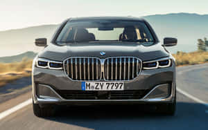 灰色BMW 7系房車在日落時分行駛在山路上。 — 1280x800 壁紙