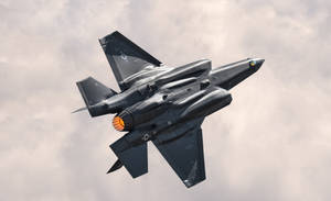 灰色戰鬥機在陰天飛行，後燃器點亮 — 軍事動圖 壁紙