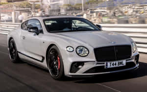銀色賓利 Continental GT 在賽道上疾馳，背景是模糊的觀眾。 — Steam Deck OLED 壁紙