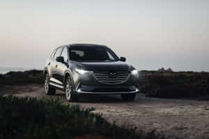 黑色Mazda CX-9 SUV停泊喺海岸泥路，暮色時分。 — Surface Laptop 壁紙