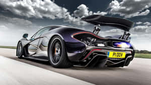 黑色McLaren P1超級跑車在跑道上疾馳，尾翼升起。 — 麥拿侖 GIF 壁紙