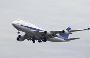 一架大型白色和藍色的波音747飛機正在下降，起落架已展開。 — MacBook Pro 16 壁紙