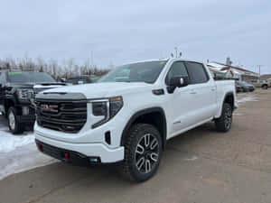 白色GMC Sierra AT4 pickup貨車停泊在雪地停車場，周圍有光禿禿的樹木。 — 5120x1440 壁紙