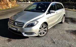 銀色 Mercedes-Benz 旅行車停泊在蜿蜒道路附近的碎石路上。 — Steam Deck 壁紙
