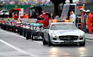 銀色 Mercedes-Benz 安全車帶領 Formula 1 賽車在濕滑賽道上。 — MacBook Pro M1 壁紙