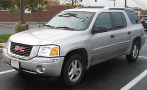 銀色GMC Envoy SUV停泊在磚牆附近的瀝青停車場。 — MacBook Air M1 壁紙