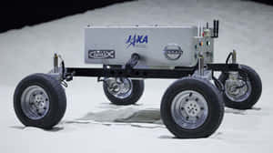 銀色月球車帶有NASA JAXA日產標誌，位於模擬月球表面。 — 月亮 壁紙