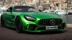 綠色RENNtech Mercedes AMG GT停泊在碼頭，旁邊有遊艇和城市建築。 — 綠色動態圖 壁紙