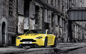 黃色Aston Martin停泊喺濕滑鵝卵石街，近舊磚建築。 — Steam Deck OLED 壁紙