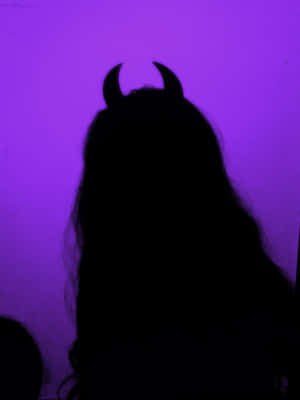 一個戴著惡魔角的人物剪影，背景是紫色光。 — 紫色花朵 壁紙