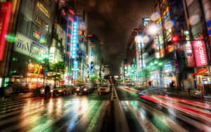 雨濕的東京街道，霓虹招牌和模糊的車燈在夜晚閃耀。 — 城市景觀 壁紙
