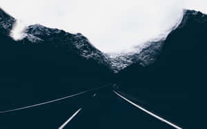 一條蜿蜒的道路穿過雪山，天空多雲。 — 黑暗森林 壁紙