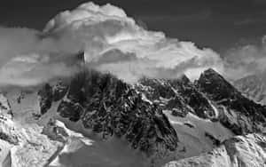 黑白照片中，積雪的山峰從濃密的雲層中浮現。 — MacBook Air M1 壁紙