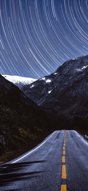 夜間山路，積雪山峰上空有星軌。 — POCO M 壁紙