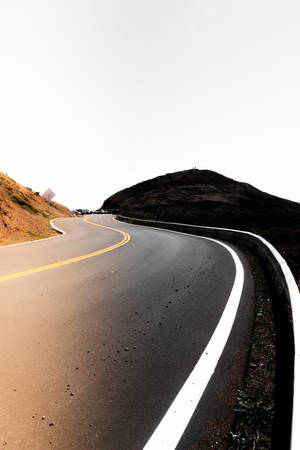 在蒼白的天空下，蜿蜒的道路穿過貧瘠的山丘 — 道路 壁紙