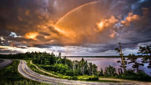 湖邊蜿蜒的道路，在壯麗的夕陽天空下，有彩虹 — 湖景 壁紙