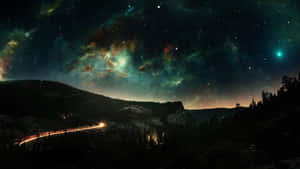 在充滿色彩繽紛星雲的星空下，一條穿過山脈的發光道路。 — 月色夜空 壁紙